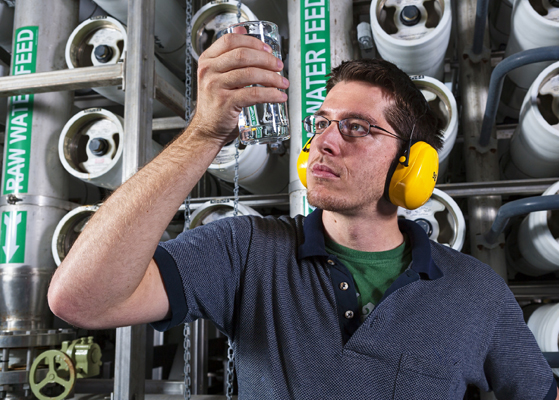 Man with yellow headset assessing water in a glass